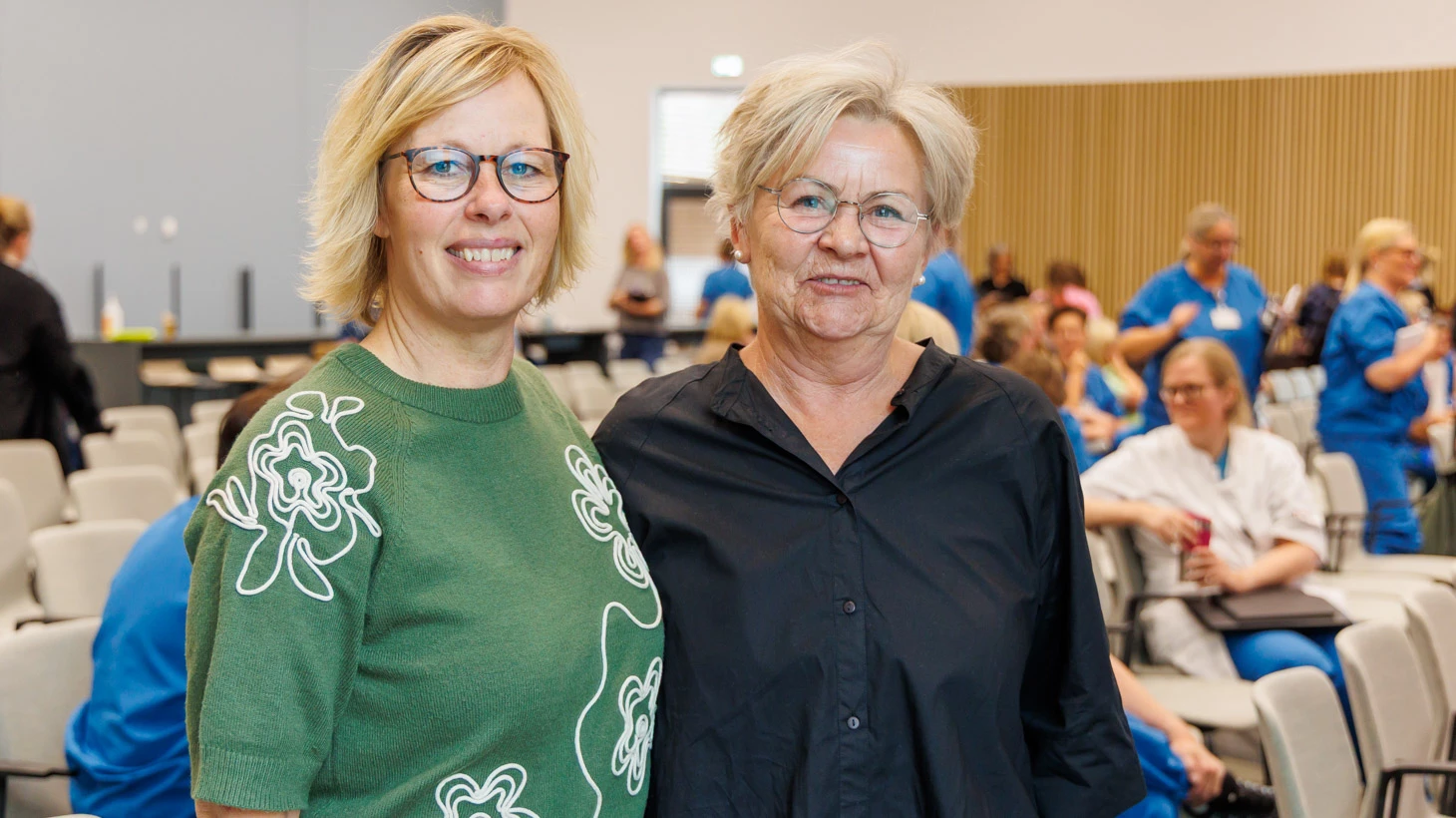 To deltagere ved TRIO-workshoppen om belastningspsykologi står sammen foran salen.