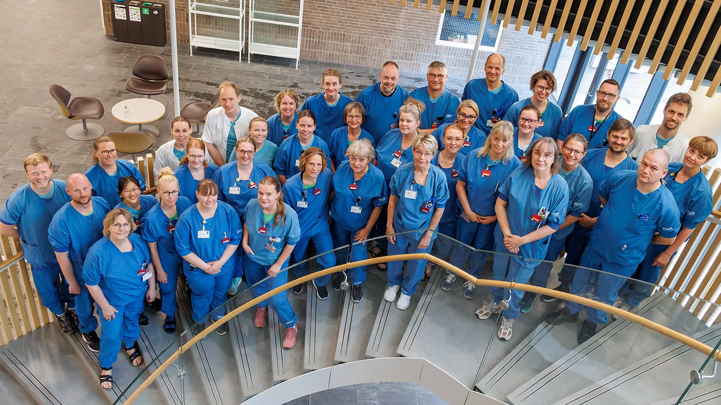 En flok medarbejdere i blåt står på trappe