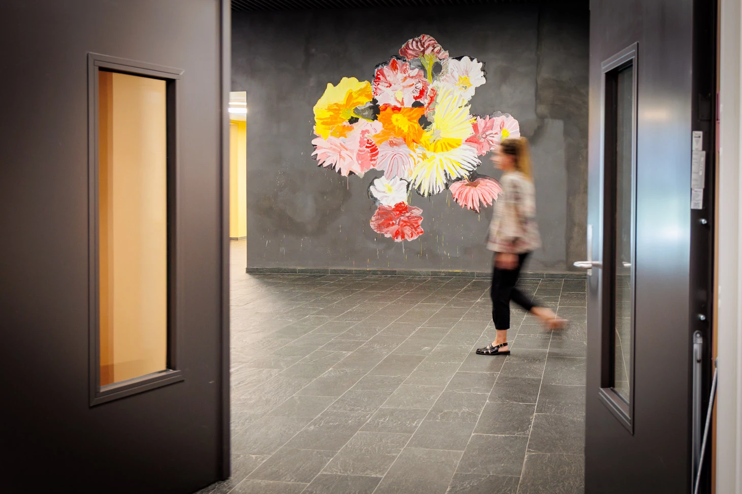 Billedet viser gående person foran kunst i foyeren