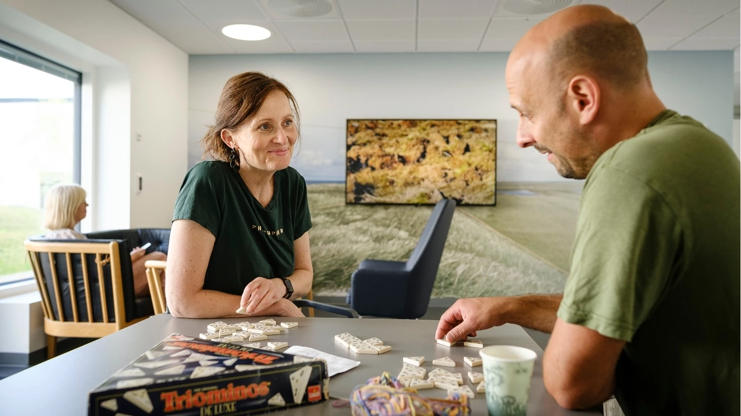 Medarbejder og patient sidder i fællesrum på psykiatrisk afdeling og spiller brætspil