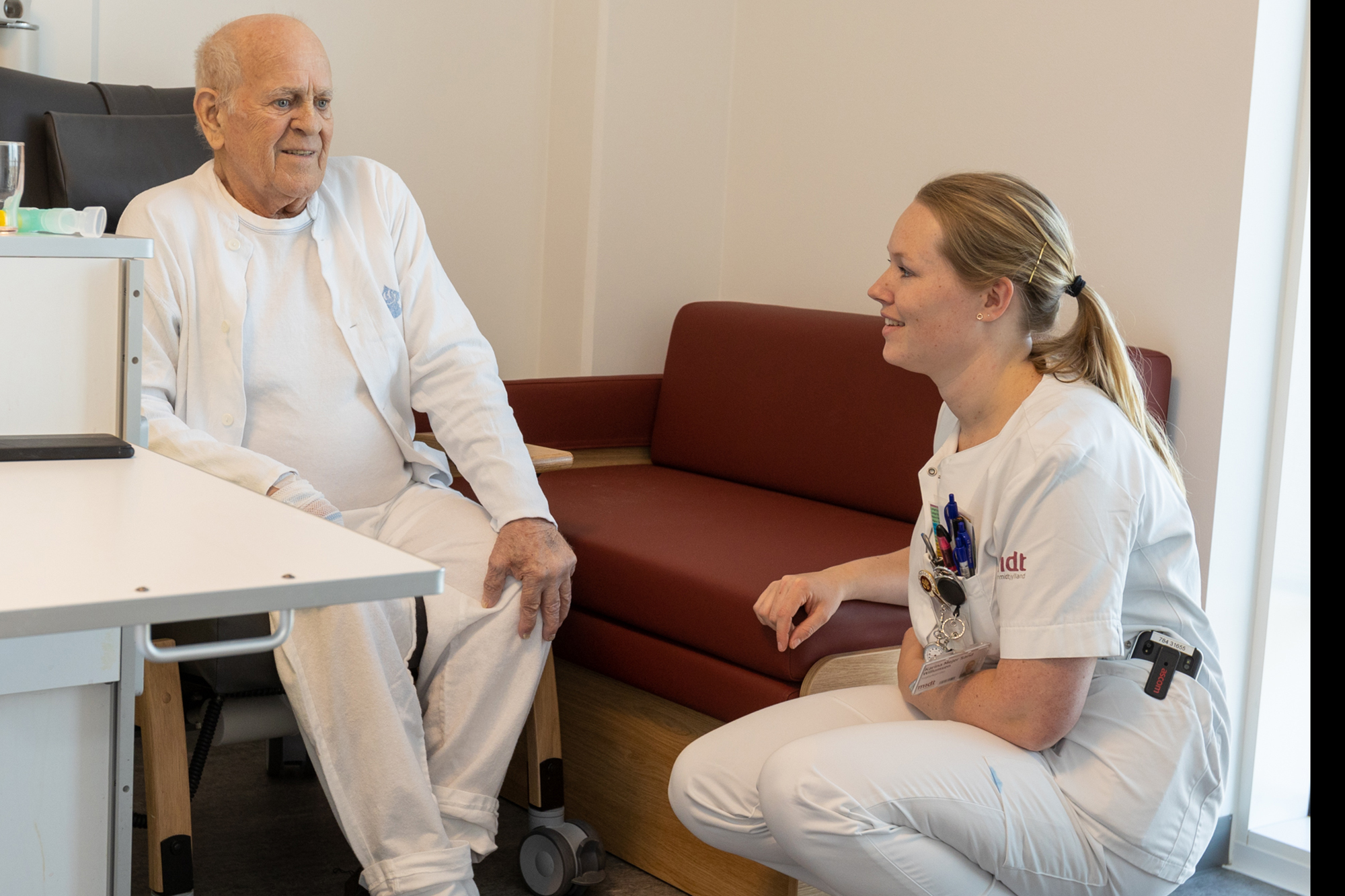 Sygeplejerske taler med patient på sengestue