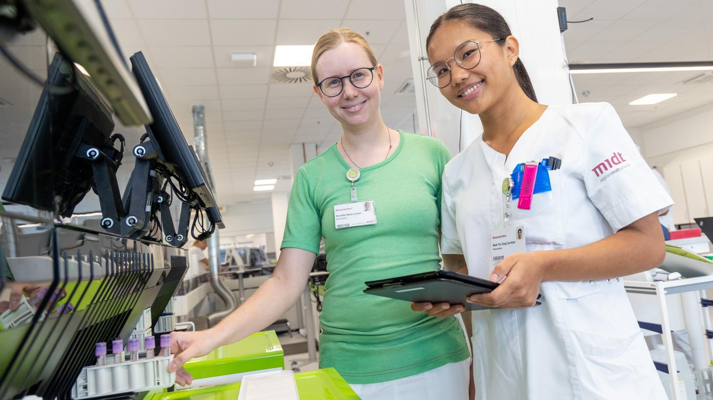 To bioanalytikere står ved en maskine, der analyserer blodprøver.