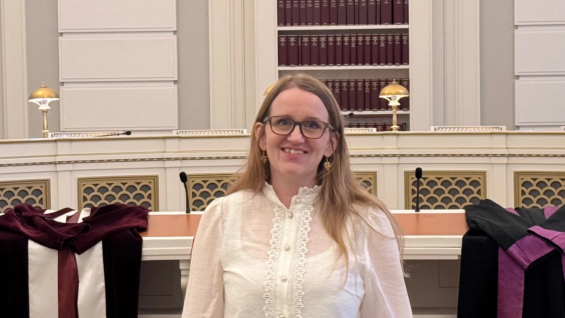 Kvinde i hvid skjorte og sorte bukser.