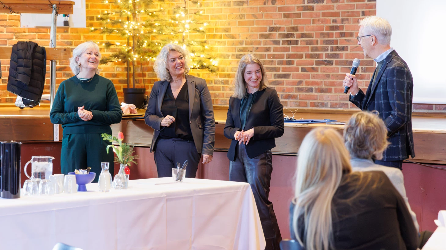 Tre kvinder taler med en mand, der holder en mikrofon.