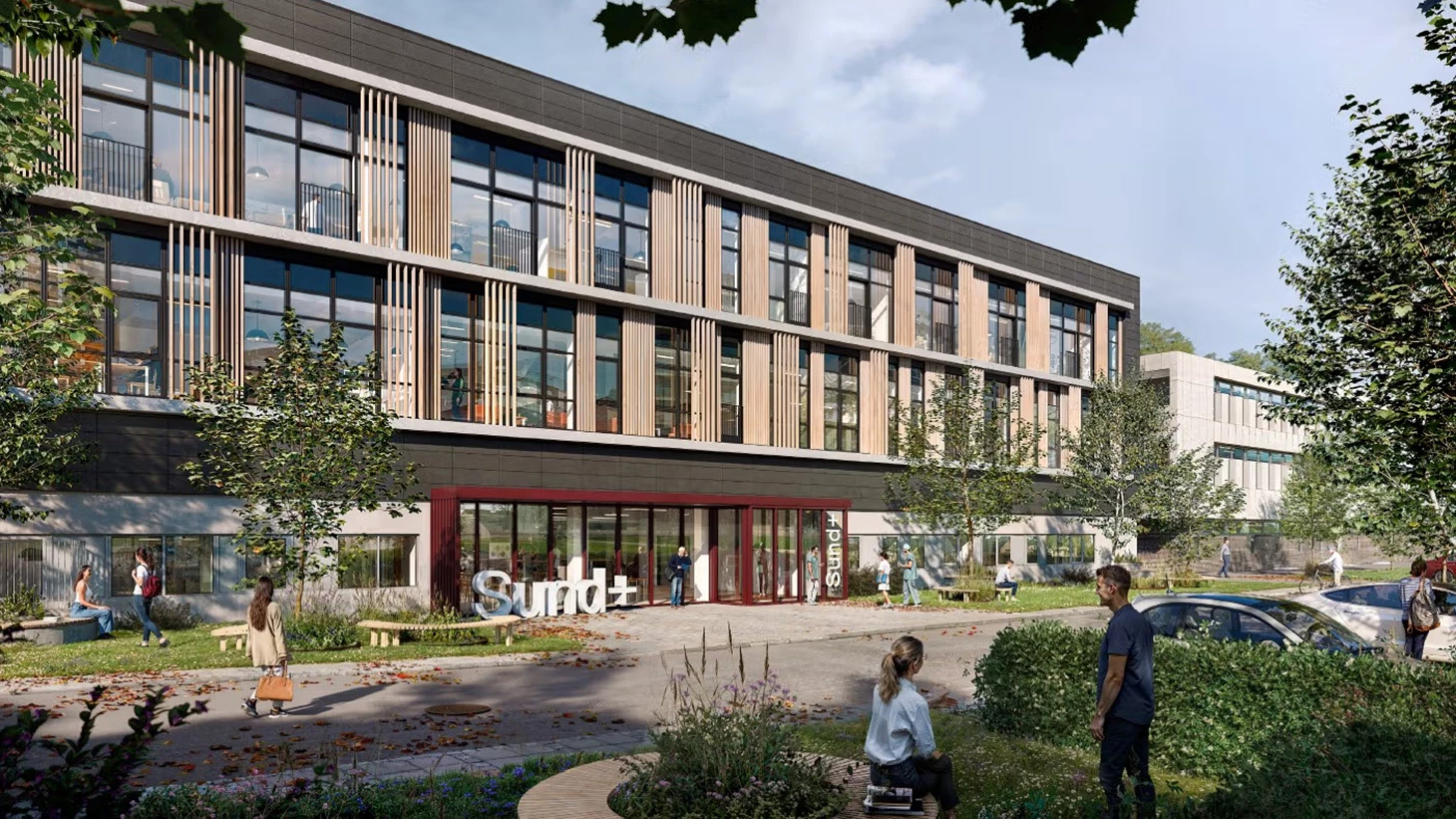 Kvinde i blåt og sort tøj med grøn natur i baggrunden.