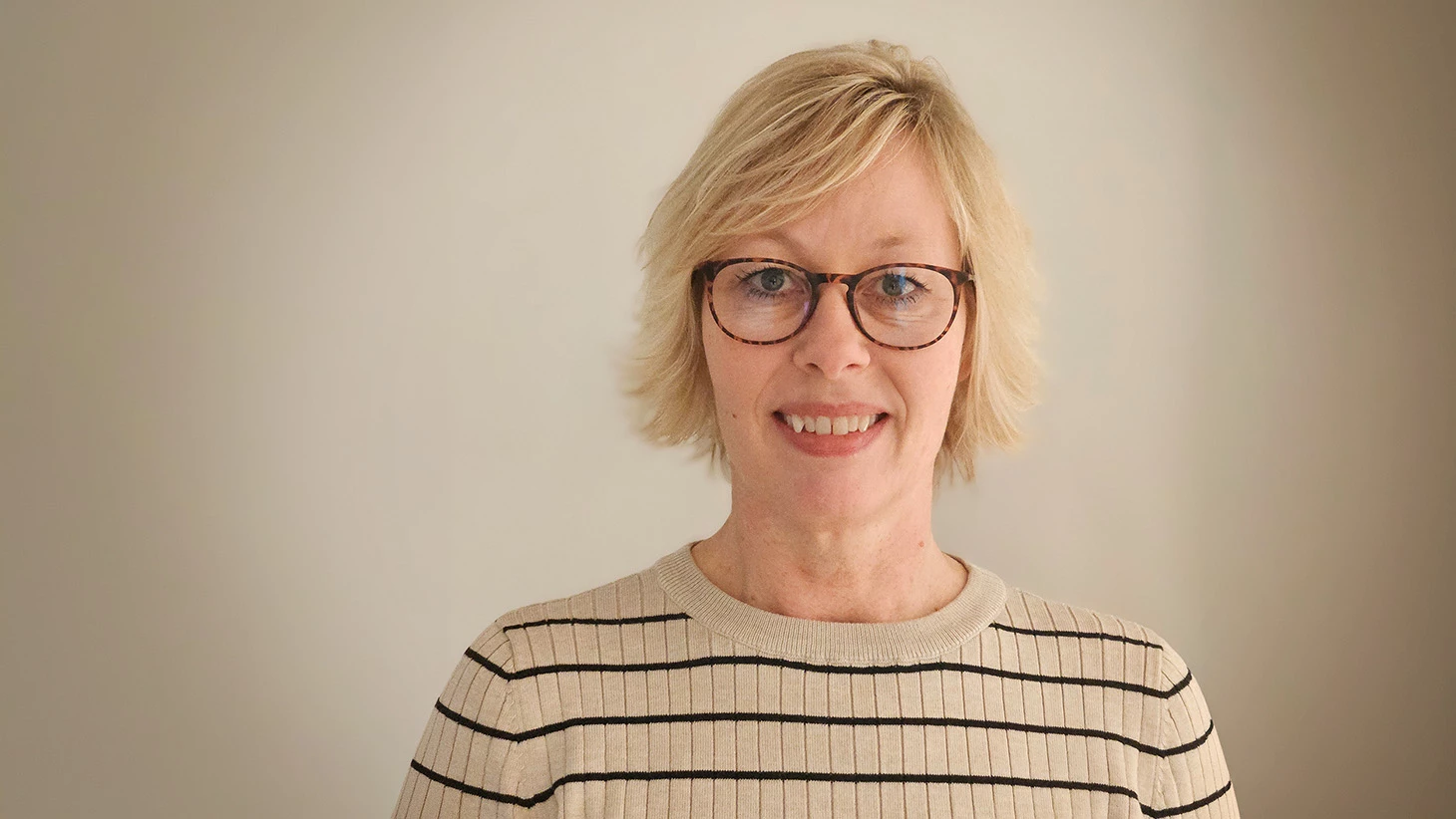 Portræt af kvinde i lys stribet striktrøje på lys baggrund